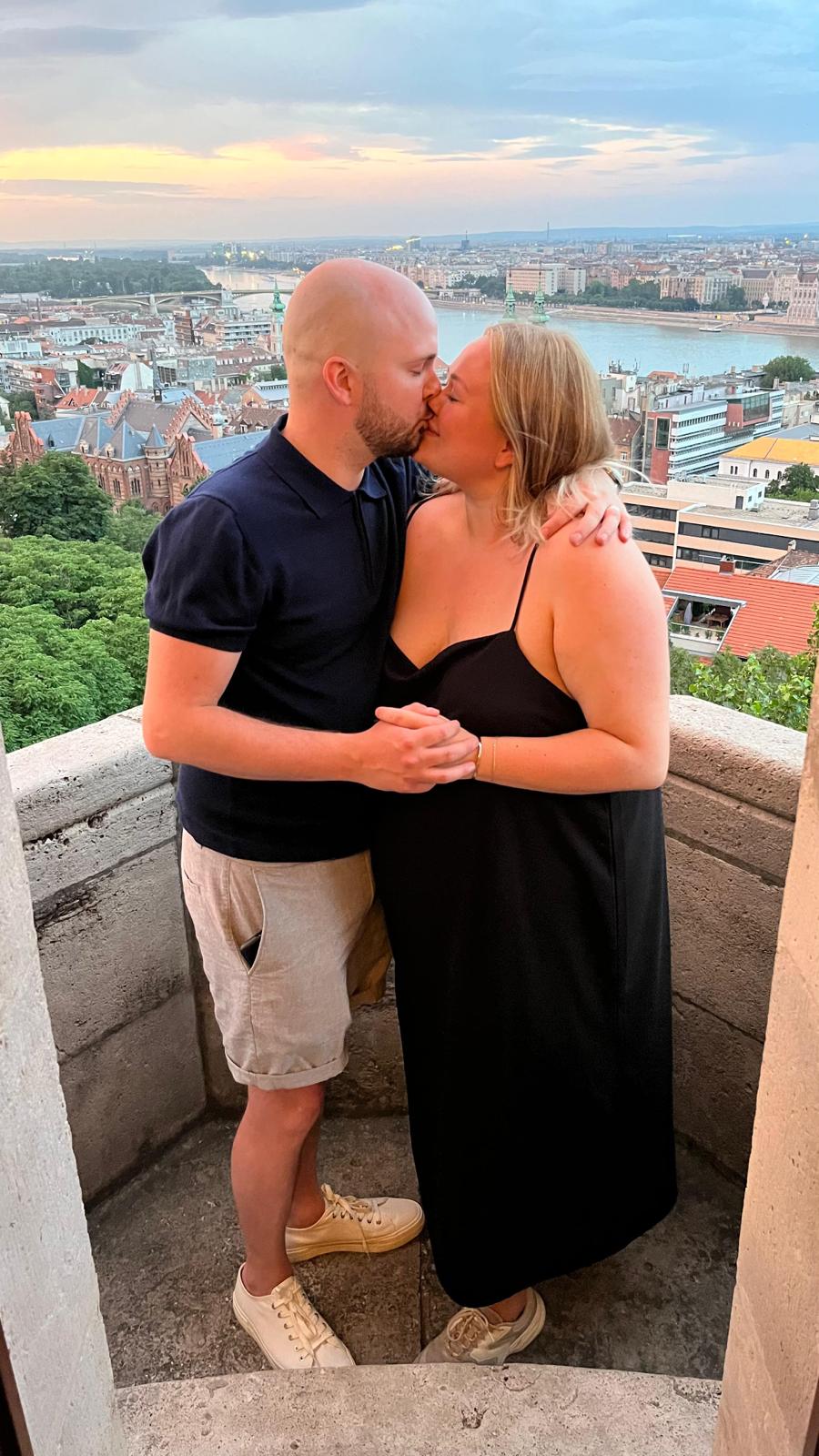 Engaged couple sharing a passionate kiss on the terrace with the backdrop of Budapest