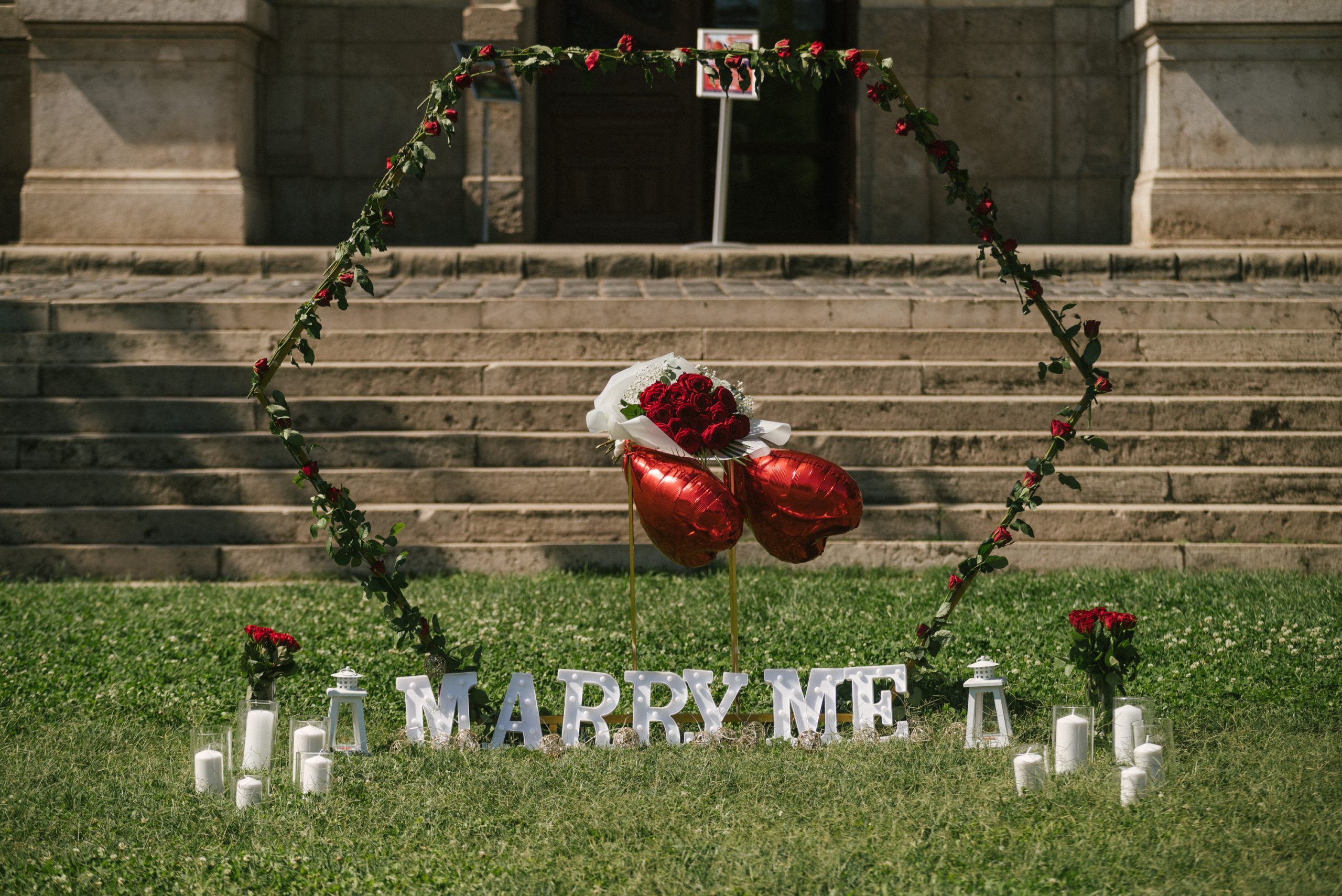 Outdoor marriage proposal setup with a heart-shaped rose arch, {{brizy_dc_image_alt imageSrc=