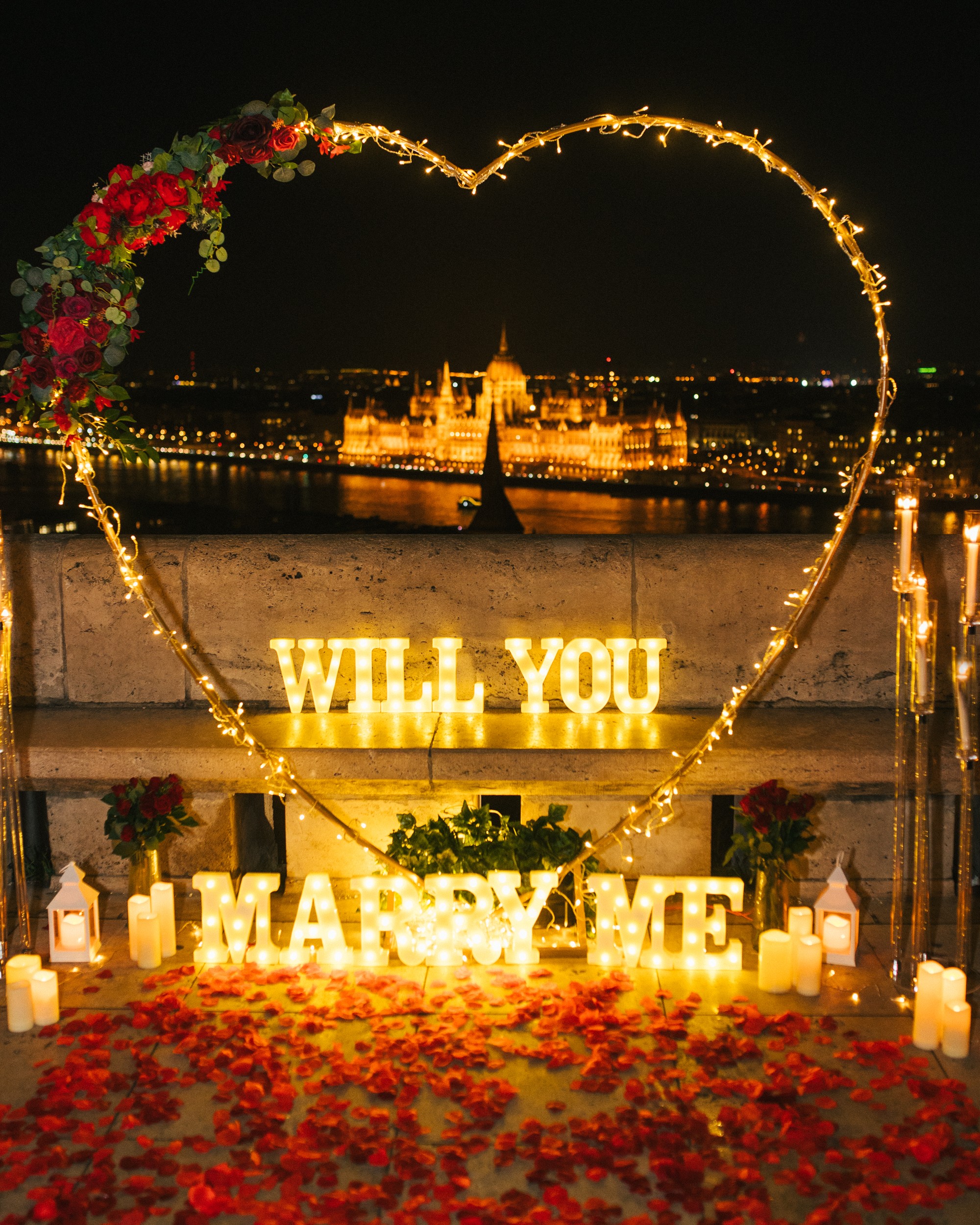 Valentine's Day engagement proposal setup in Budapest with romantic lights and rose petals {{brizy_dc_image_alt imageSrc=