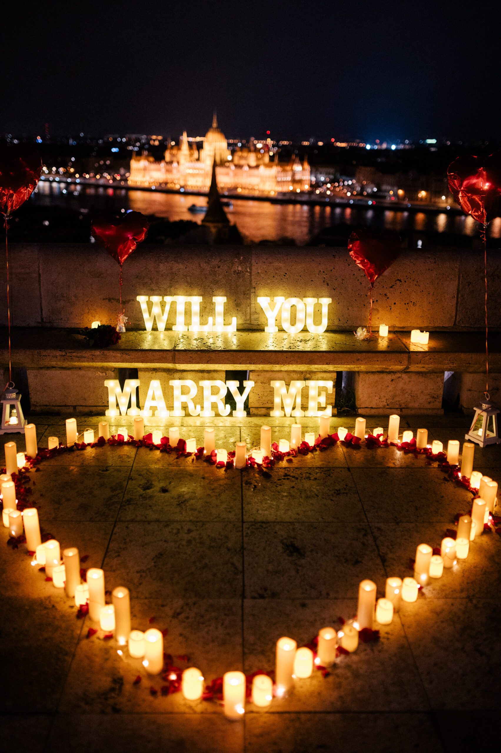 A romantic marriage proposal setup at night in Budapest, featuring glowing {{brizy_dc_image_alt imageSrc=