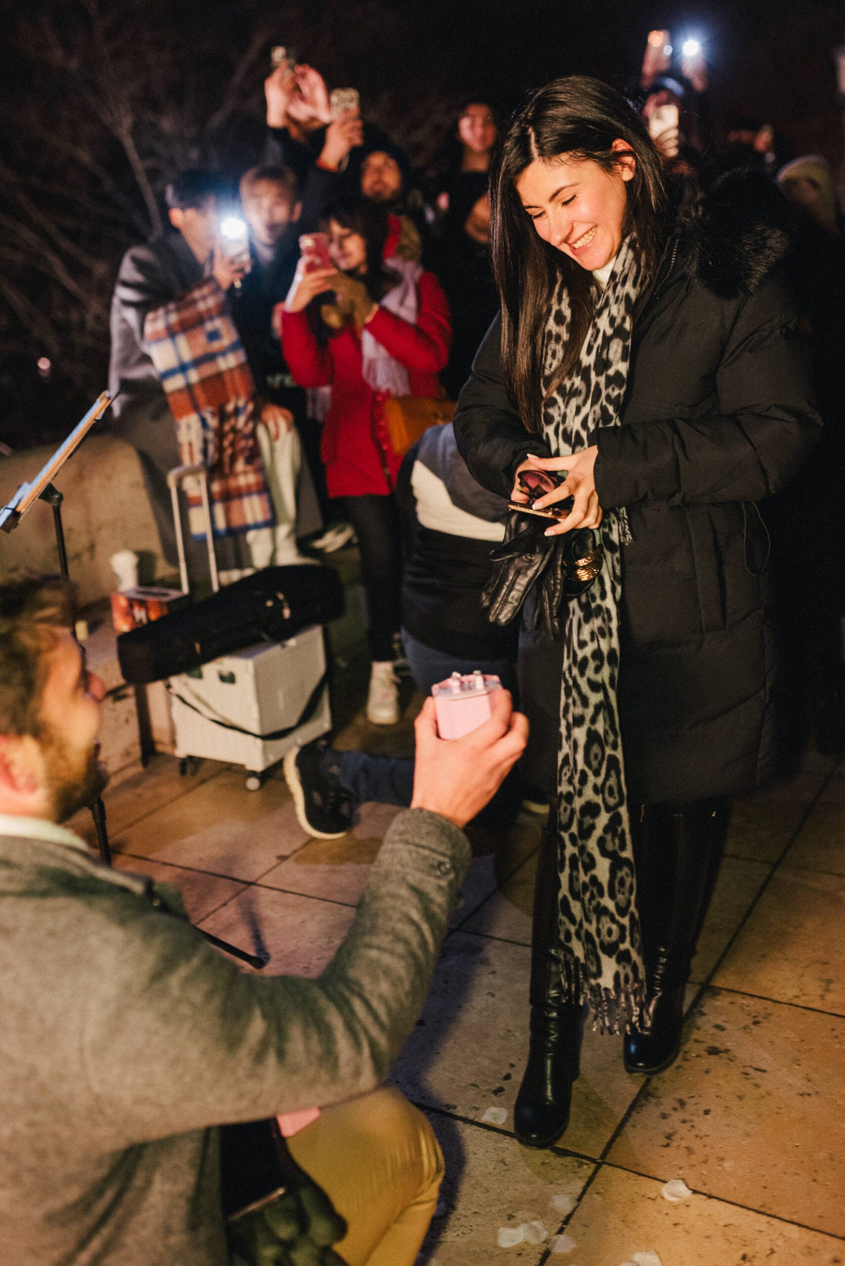 Proposal at Fisherman’s Bastion in Budapest with large crowd gathered, violin player, and rose petal arrangement {{brizy_dc_image_alt imageSrc=