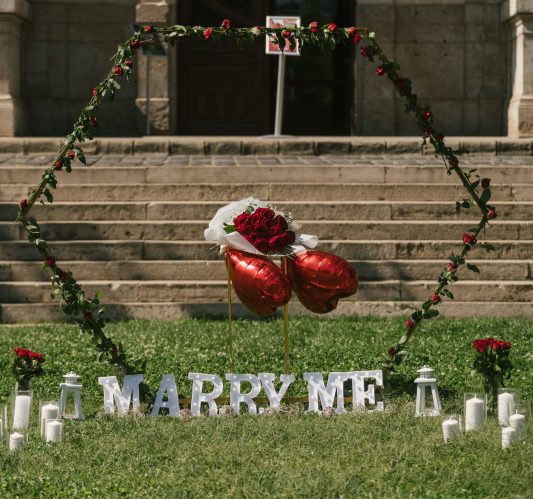 Outdoor marriage proposal setup with a heart-shaped rose arch, 