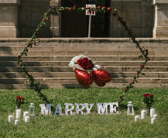 Outdoor marriage proposal setup with a heart-shaped rose arch, 