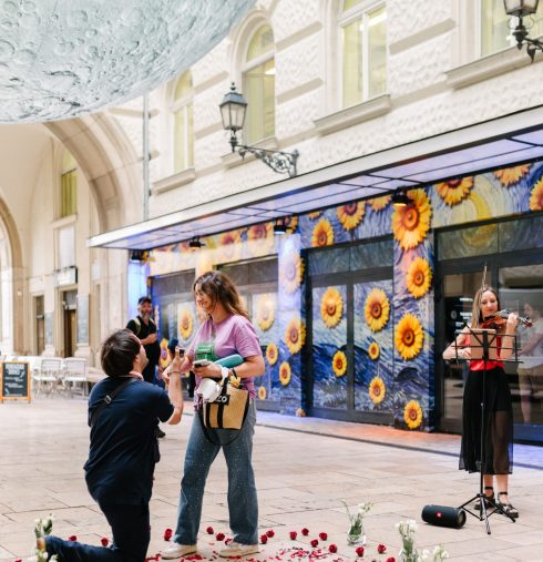 Proposal in Budapest's historic center with a moon installation, rose petals, and a violinist creating a romantic atmosphere