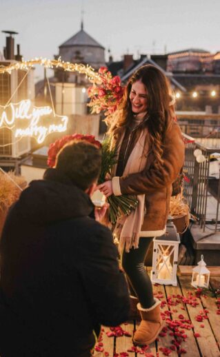 Close-up of an engagement ring and a bouquet of red roses during a romantic rooftop proposal in Budapest {{brizy_dc_image_alt imageSrc=