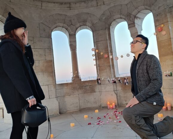 Férfi letérdel egy romantikus lánykérés során Budapesten, miközben párja meglepődve reagál {{brizy_dc_image_alt imageSrc=