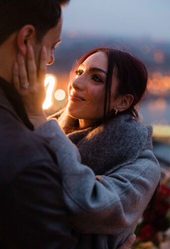 Emotional surprise engagement moment in Budapest, Hungary – a bride-to-be gazes lovingly at her fiancé after a romantic proposal. {{brizy_dc_image_alt imageSrc=
