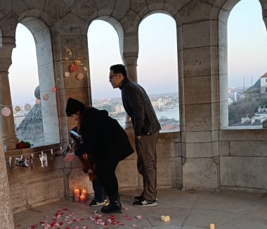 Couple looking at displayed photos and smiling during a surprise proposal at Buda Castle in Hungary