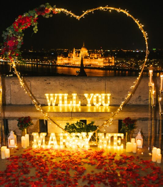Valentine's Day engagement proposal setup in Budapest with romantic lights and rose petals {{brizy_dc_image_alt imageSrc=
